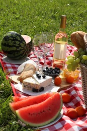 Picnic blanket with delicious food and wine outdoors on summer day