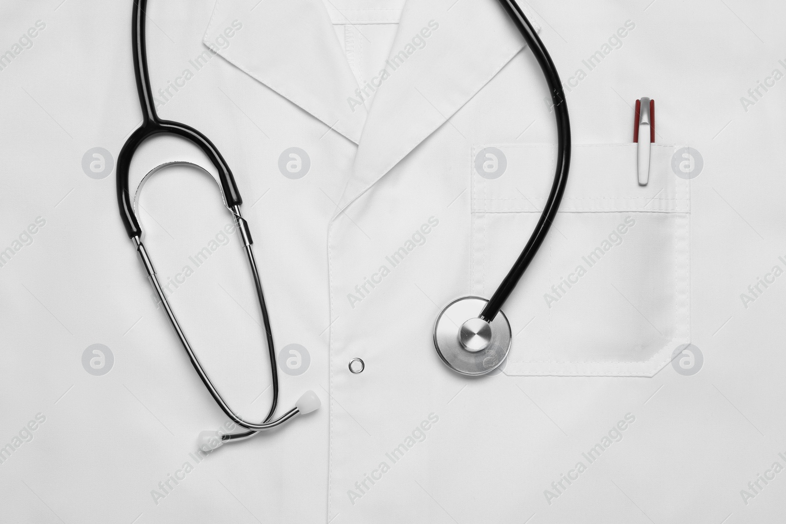 Photo of Stethoscope on white medical uniform, top view