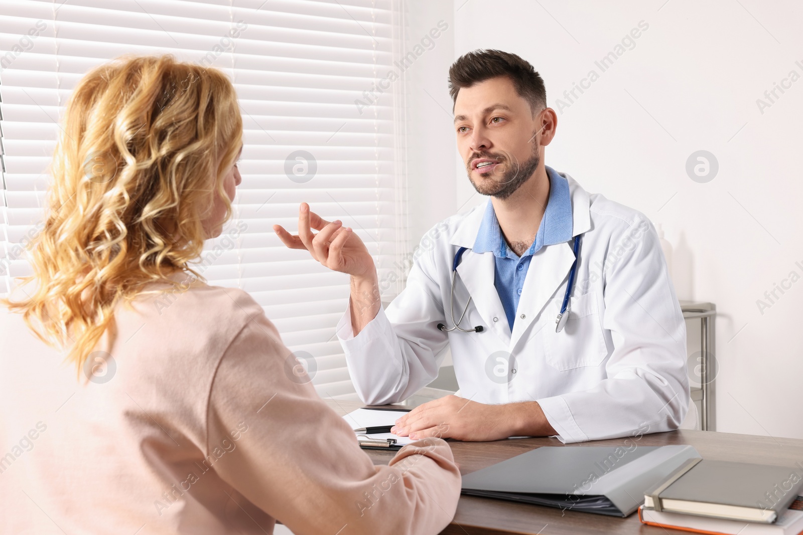 Photo of Doctor consulting patient at table in clinic