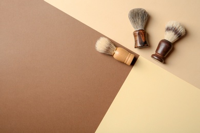 Flat lay composition with men's shaving brushes and space for text on color background