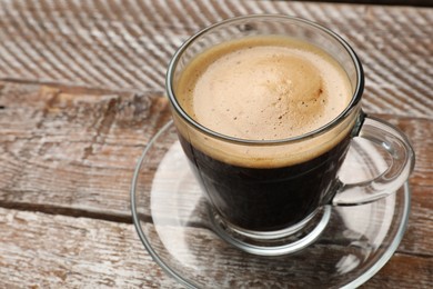 Photo of Cup of aromatic coffee on wooden table, closeup. Space for text