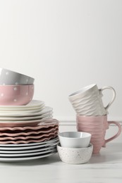 Photo of Beautiful ceramic dishware and cups on white marble table