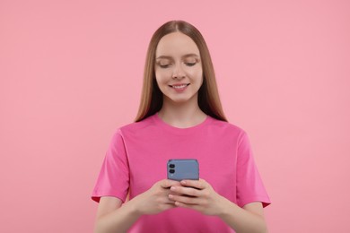 Photo of Happy young woman using smartphone on pink background