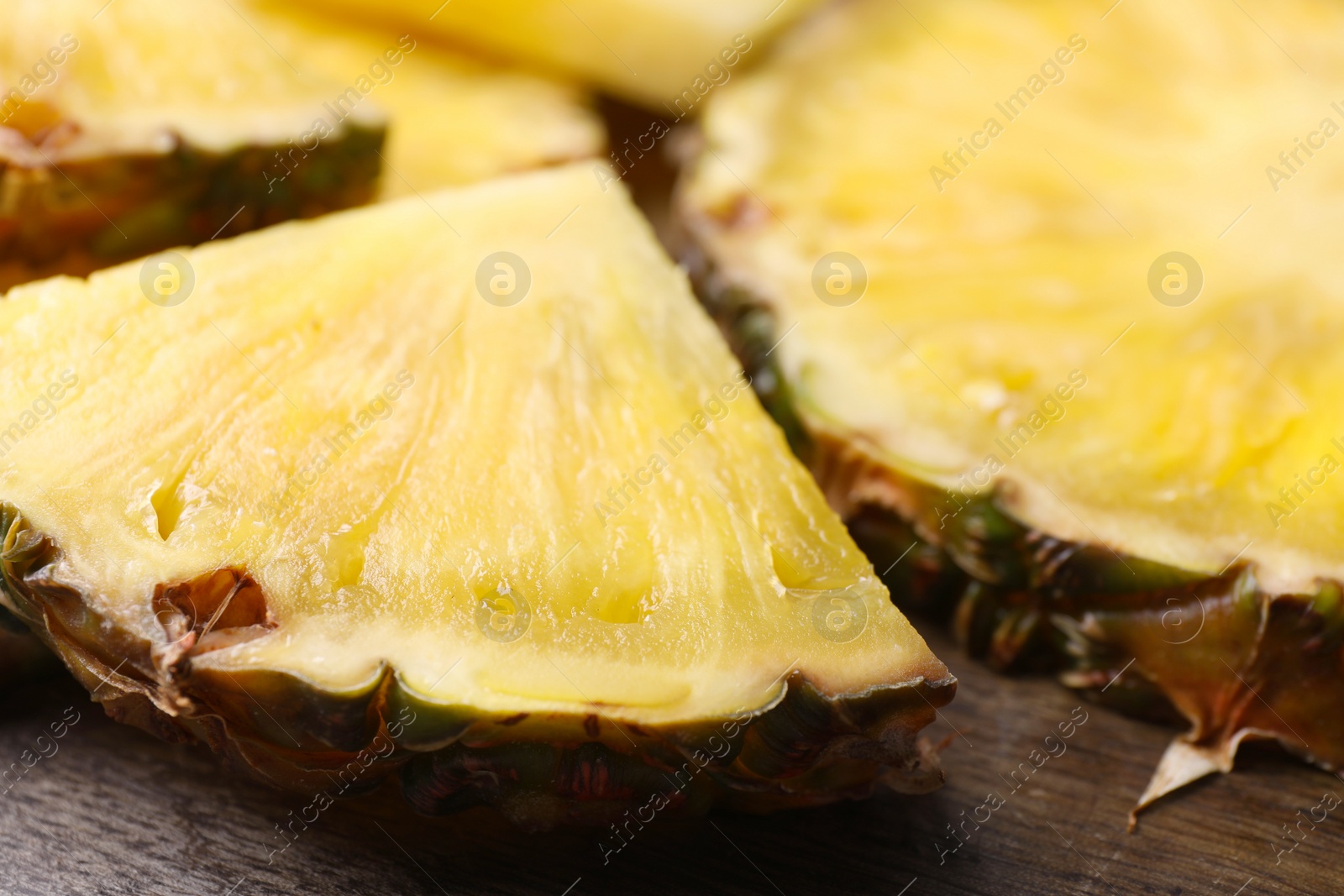 Photo of Pieces of tasty ripe pineapple on wooden table, closeup