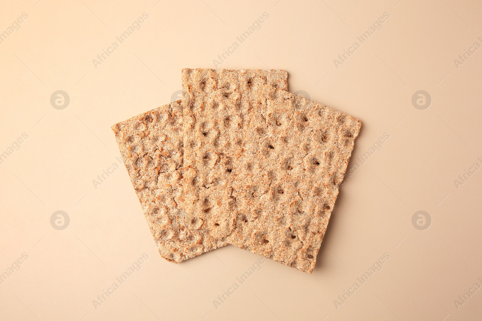 Photo of Fresh crunchy crispbreads on beige background, flat lay