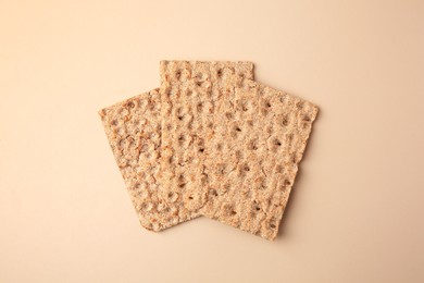 Fresh crunchy crispbreads on beige background, flat lay