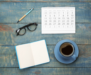 Flat lay composition with calendar and cup of coffee on light blue wooden table