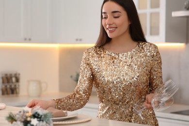 Photo of Happy woman serving table for Christmas in kitchen