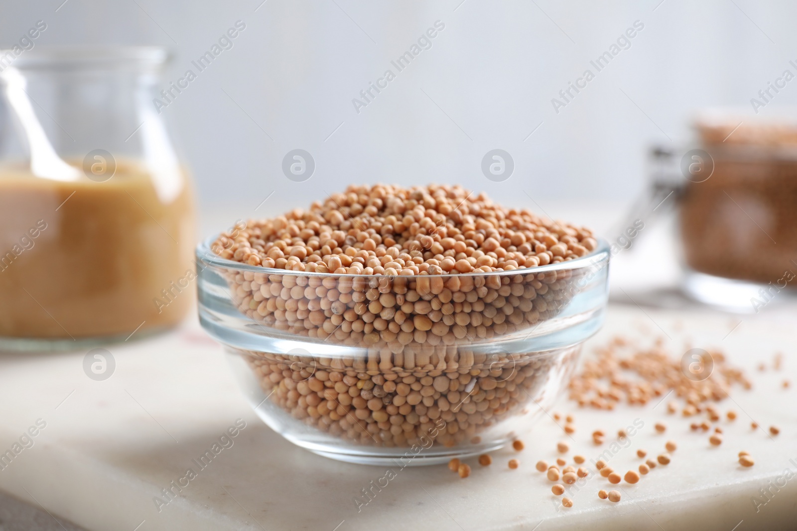 Photo of Mustard seeds in glass bowl on board, closeup.