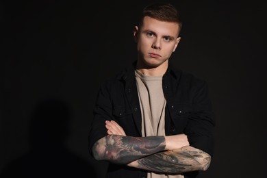 Young man with tattoos on black background. Space for text