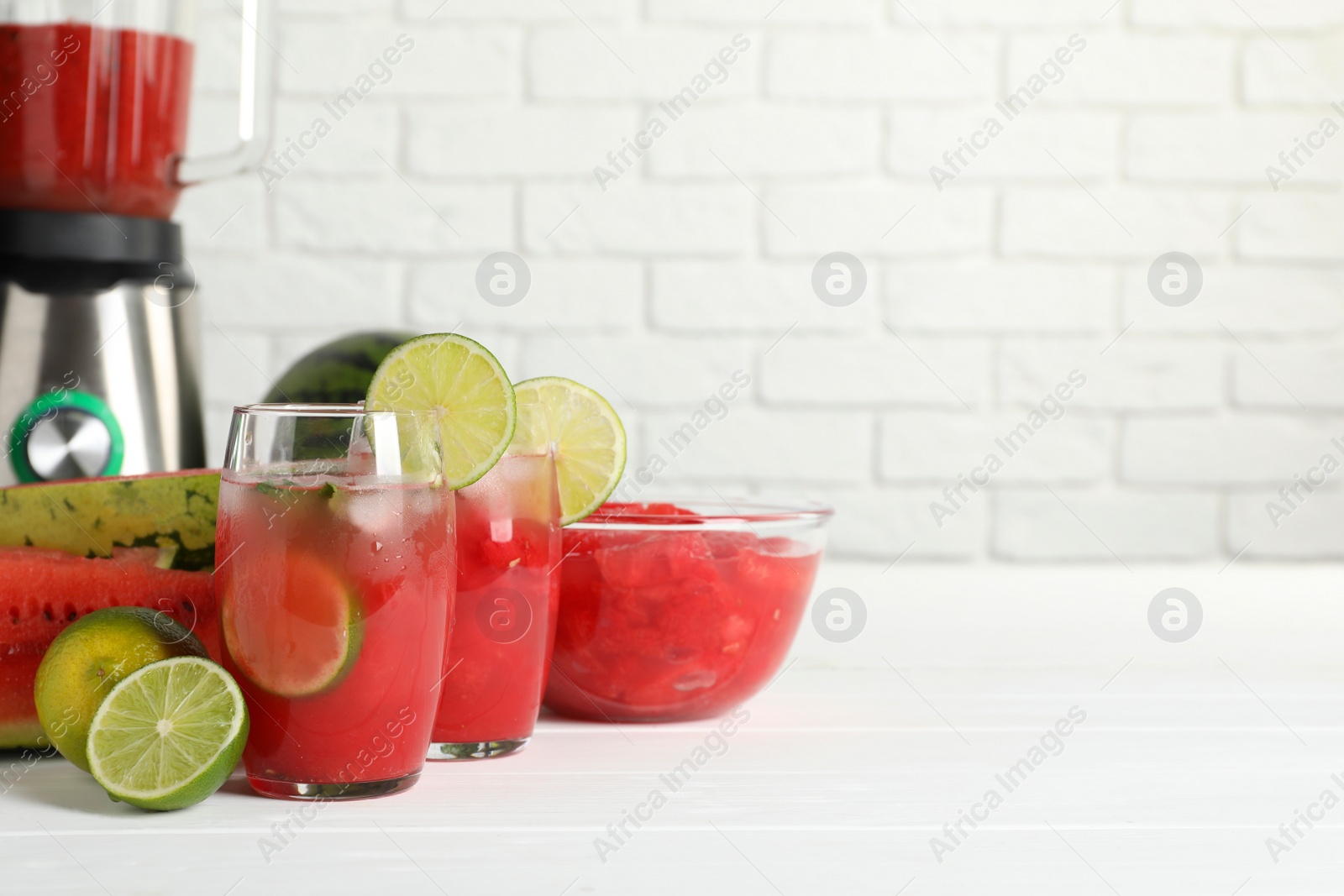 Photo of Fresh watermelon drink with lime and ingredients on white wooden table, space for text