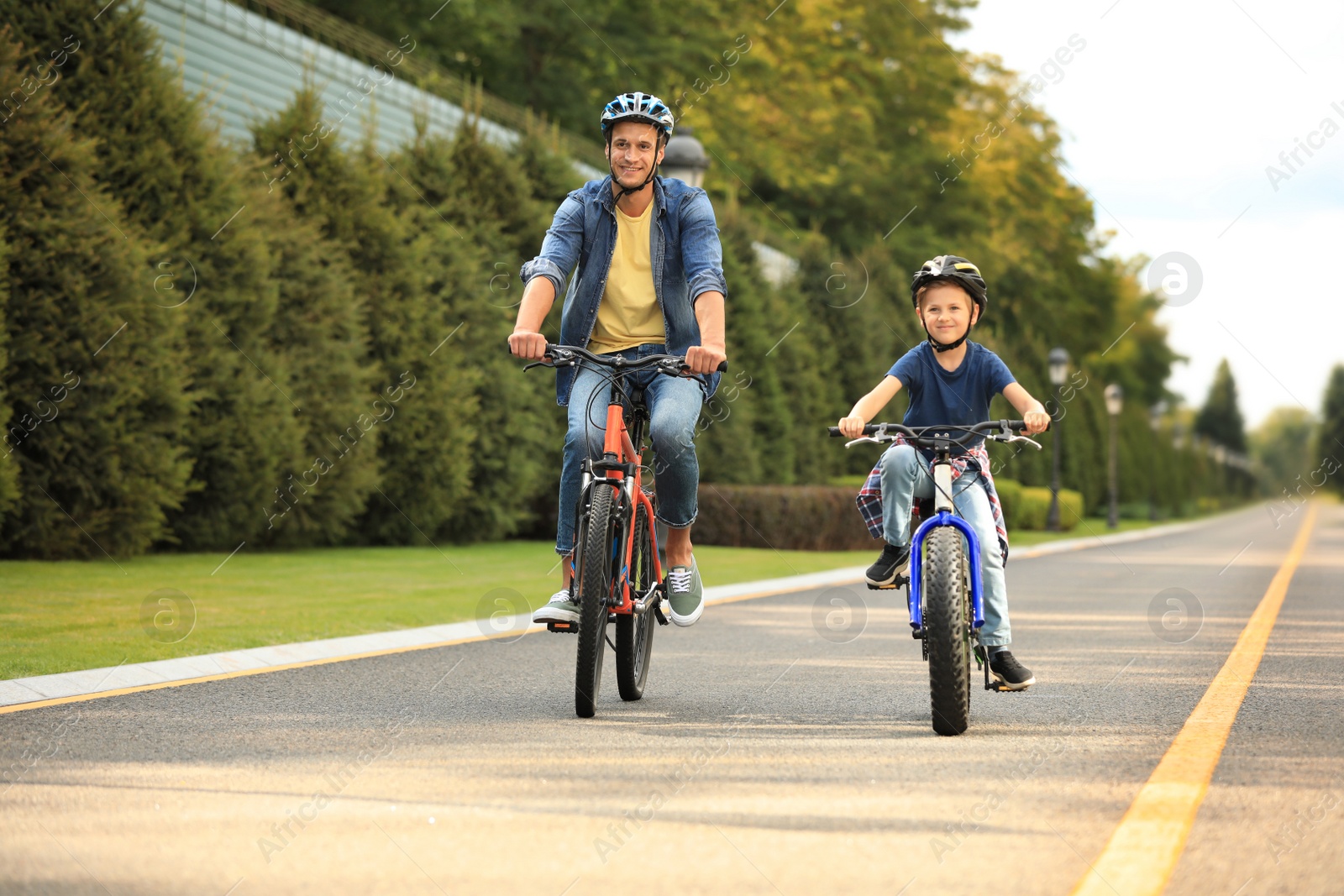 Photo of Dad and son riding modern bicycles outdoors