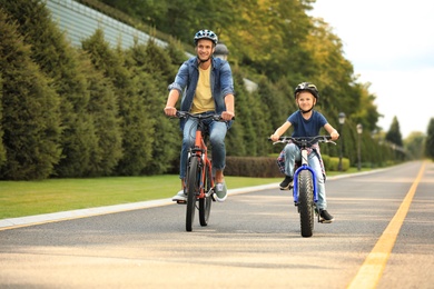 Photo of Dad and son riding modern bicycles outdoors