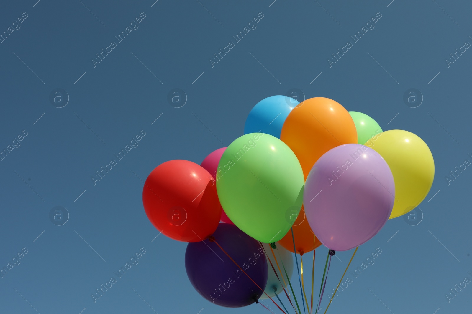 Photo of Bunch of colorful balloons against blue sky. Space for text