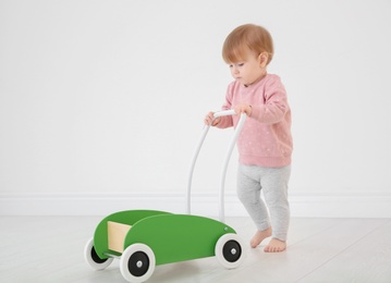 Photo of Cute baby playing with toy walker, indoors