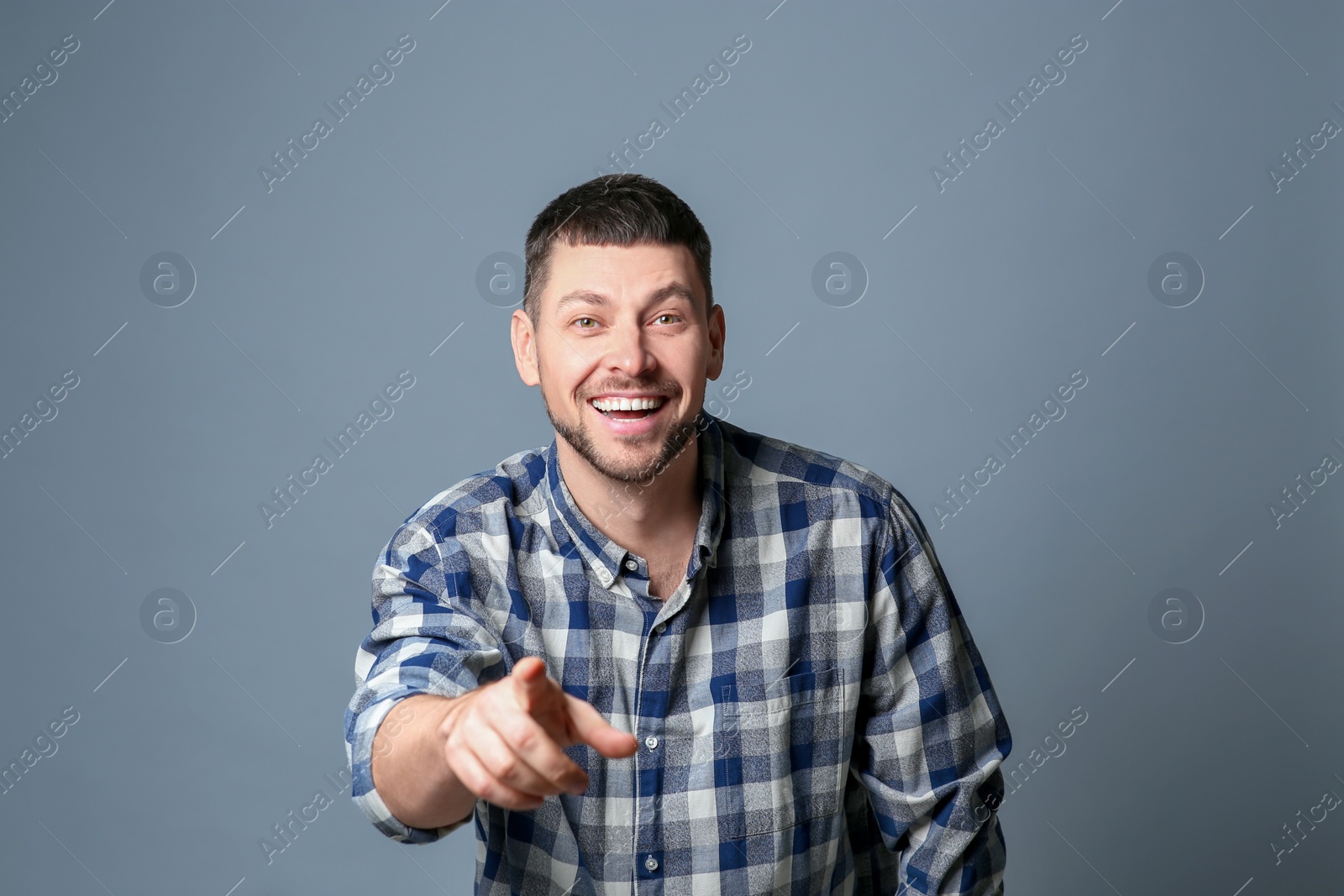 Photo of Handsome man laughing on grey background. Funny joke