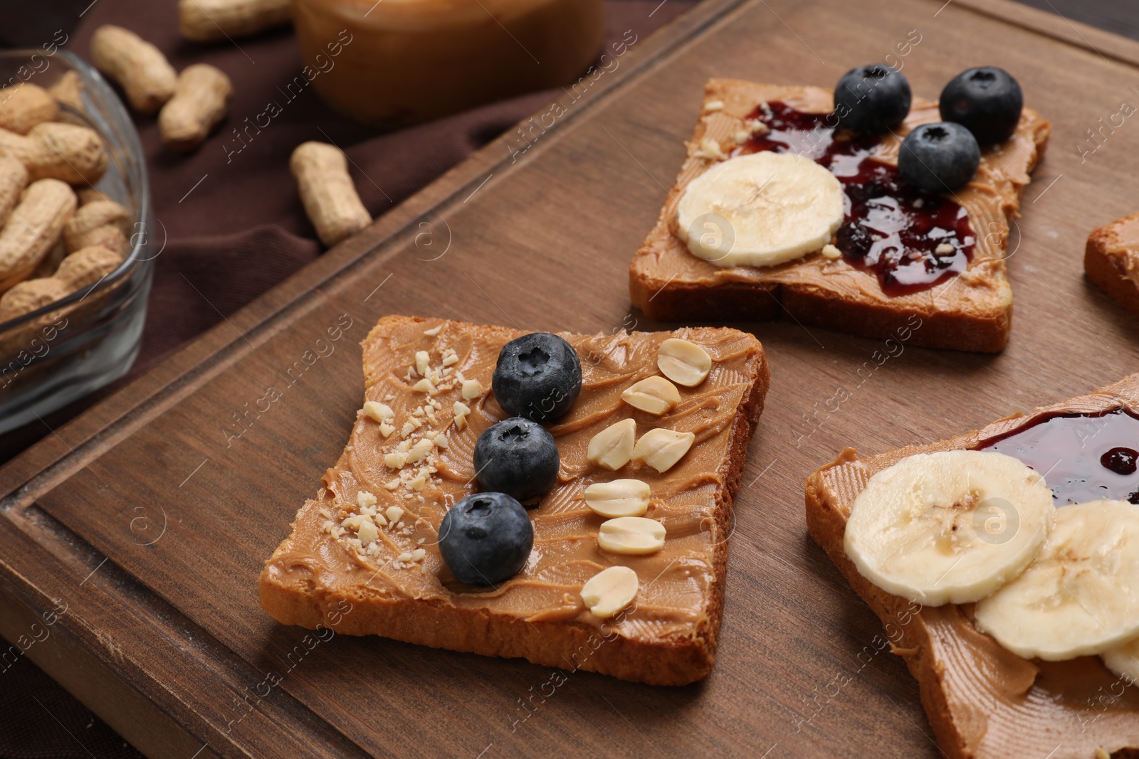 Photo of Different tasty toasts with nut butter and products on table, closeup