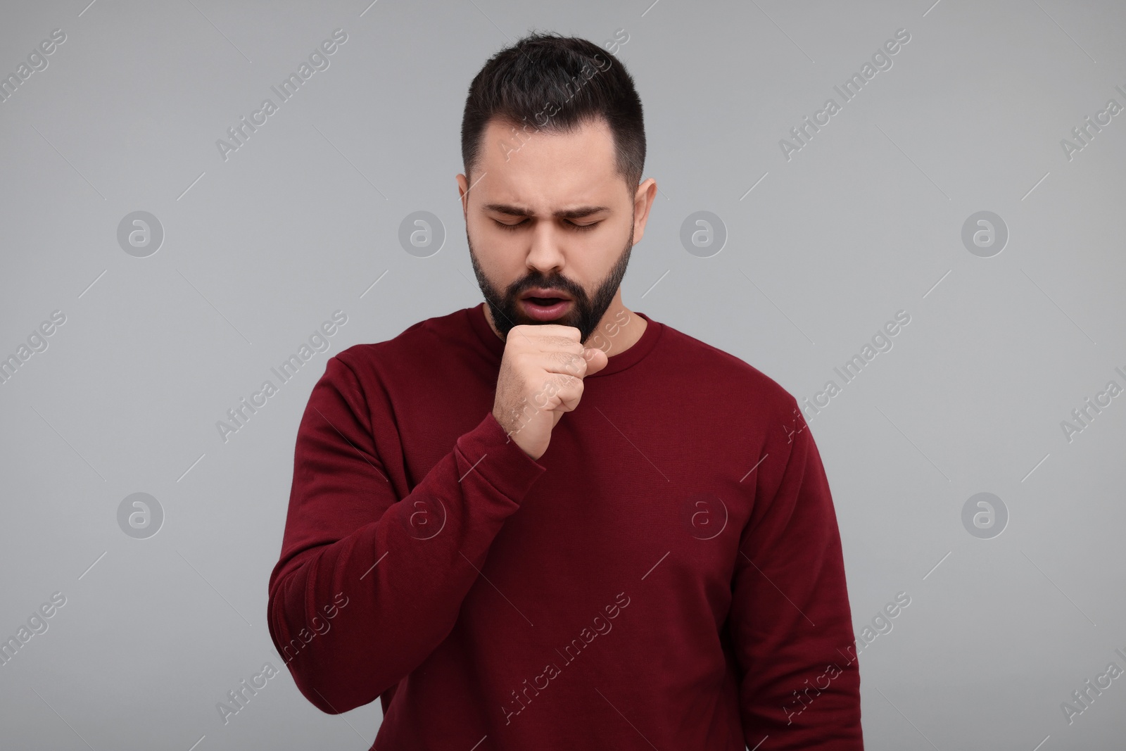 Photo of Sick man coughing on gray background. Cold symptoms