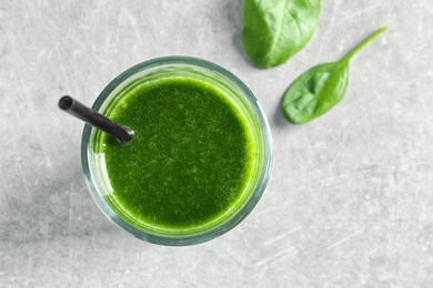 Photo of Glass with delicious detox juice and spinach on light background, top view