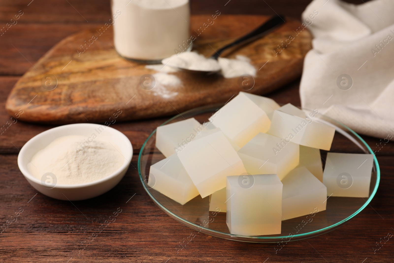 Photo of Agar-agar jelly cubes and powder on wooden table