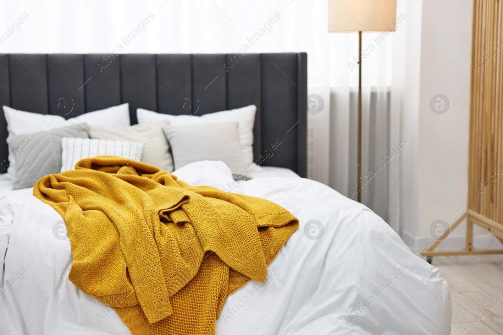 Photo of Bright plaid on bed in stylish bedroom