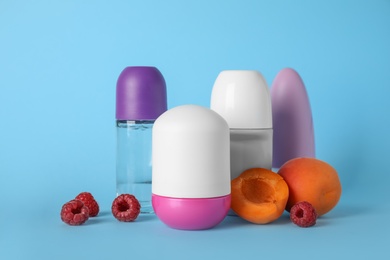 Different female roll-on deodorants, apricots and raspberries on light blue background