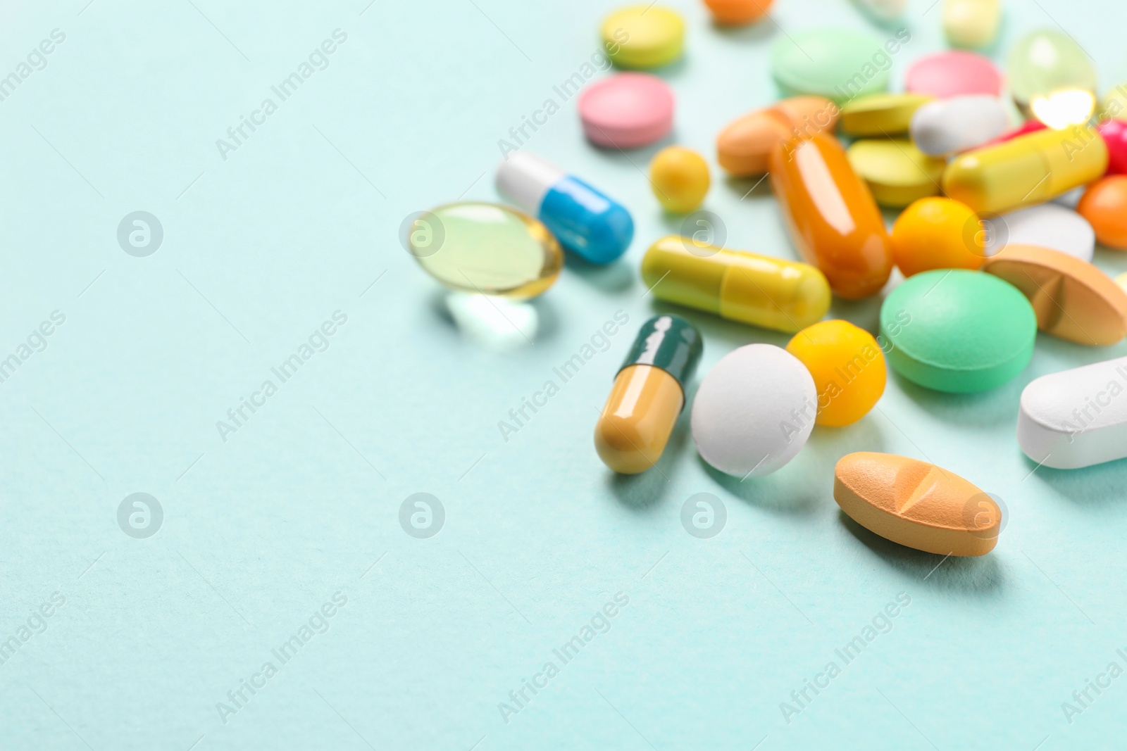 Photo of Many different pills on light blue background, closeup. Space for text