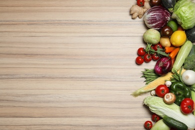 Different fresh vegetables on wooden table, flat lay. Space for text