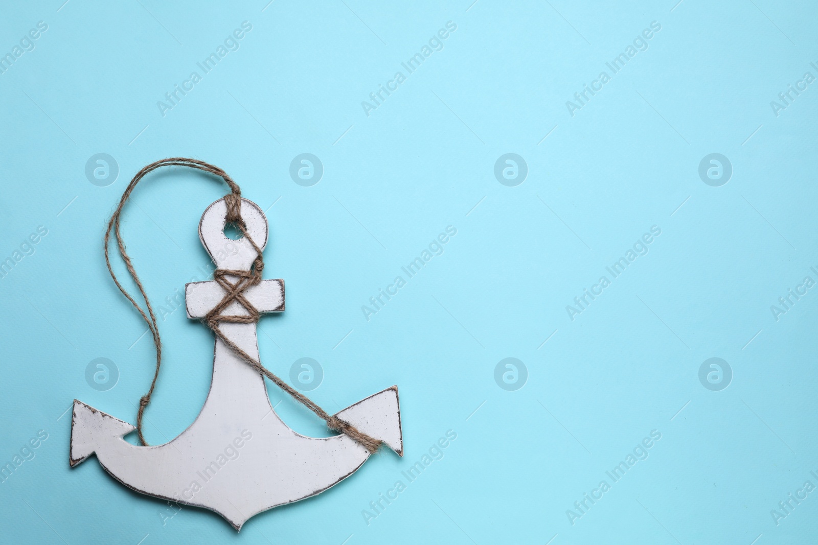 Photo of White wooden anchor figure on light blue background, top view. Space for text