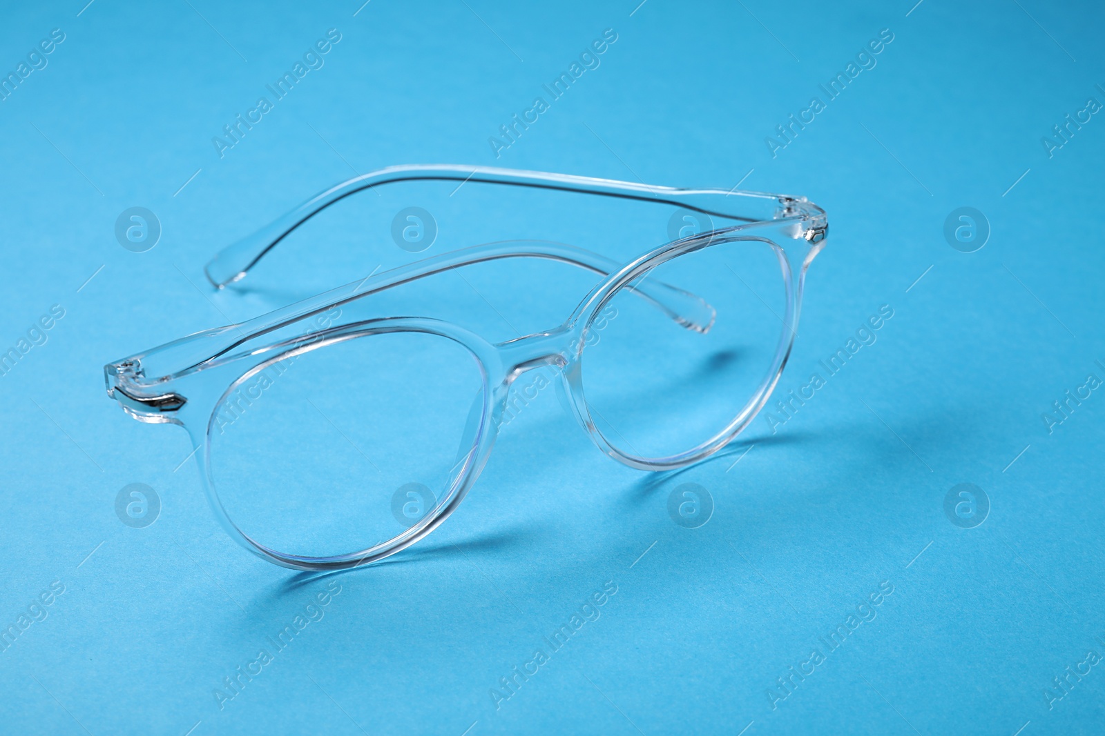 Photo of Glasses in stylish frame on light blue background