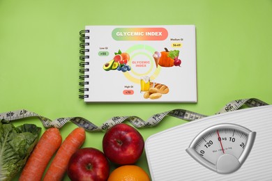 Image of Information about grouping of products under their glycemic index. Notebook, measuring tape, floor scale, fruits and vegetables on light green background, flat lay
