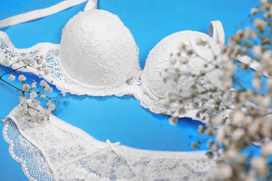 Photo of Elegant white women's underwear and gypsophila flowers on light blue background