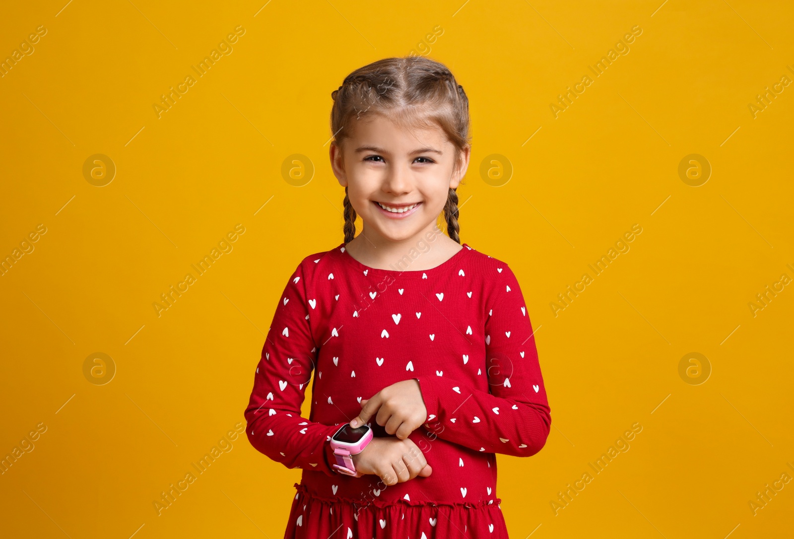 Photo of Little girl with smart watch on yellow background