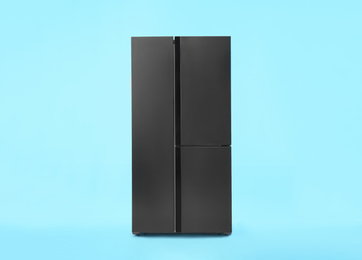 Photo of Modern stainless steel refrigerator on blue background