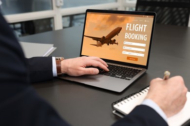 Image of Man using laptop to book flight at black table, closeup