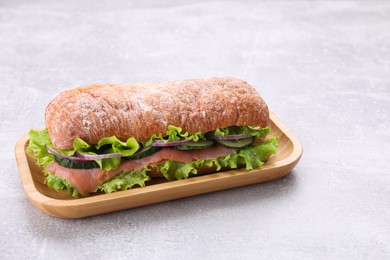 Photo of Delicious sandwich with fresh vegetables and salmon on light gray table. Space for text