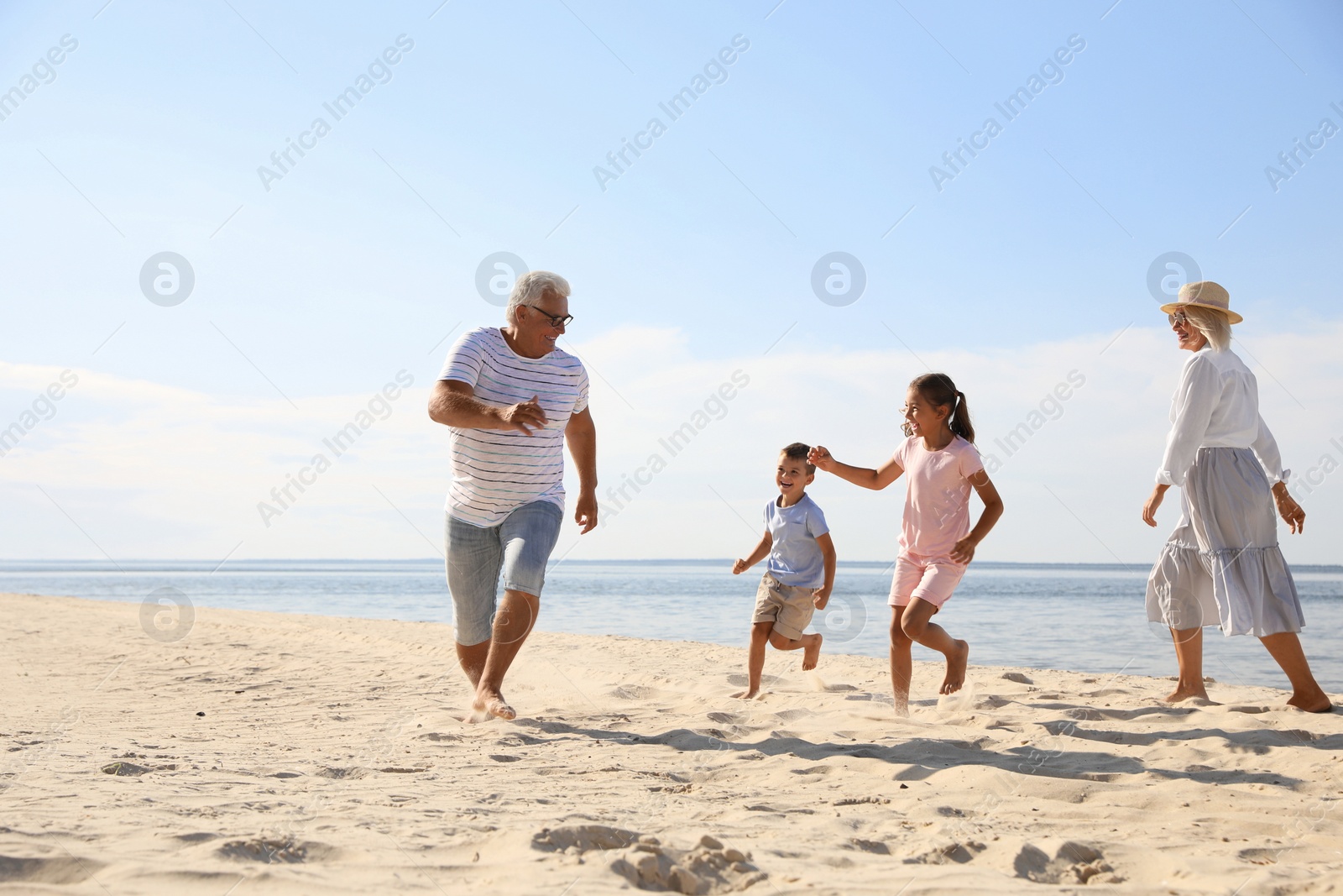 Photo of Cute little children with grandparents spending time together on sea beach