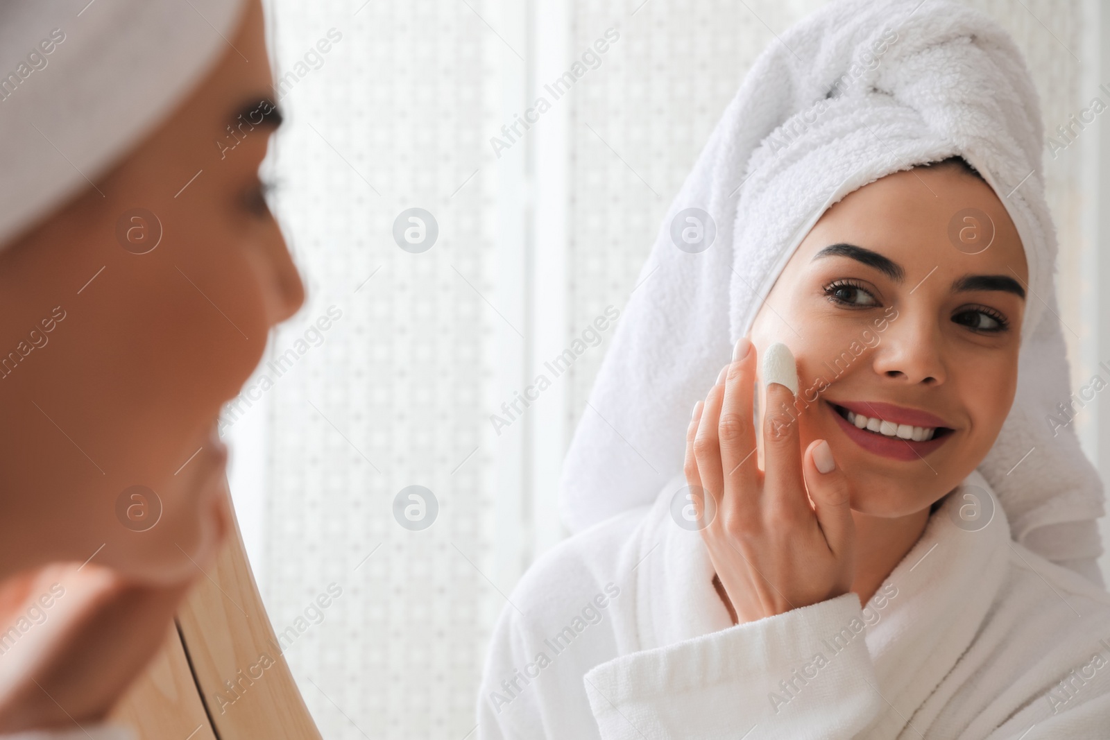 Photo of Woman using silkworm cocoon in skin care routine near mirror at home