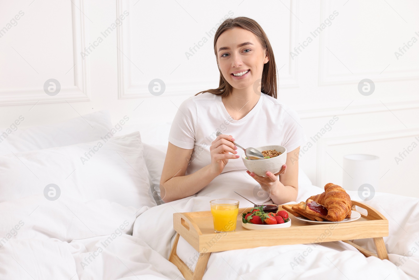 Photo of Smiling woman having breakfast in bed at home. Space for text