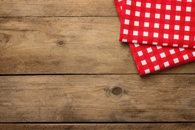 Photo of Checkered tablecloth on wooden table, top view. Space for text