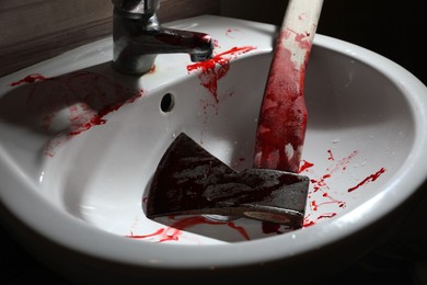 Axe with blood in sink indoors, closeup