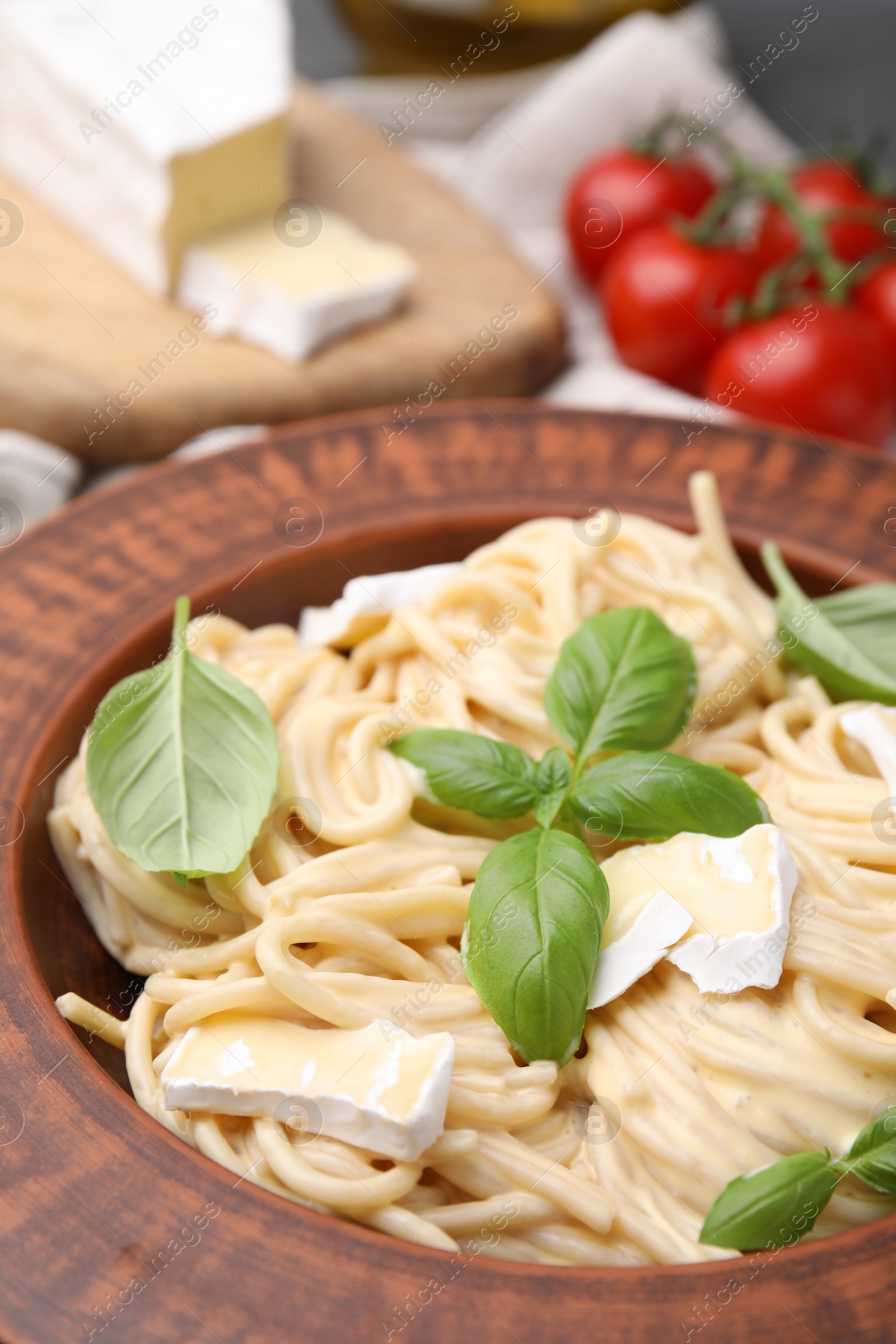 Photo of Delicious pasta with brie cheese and basil leaves on table, closeup