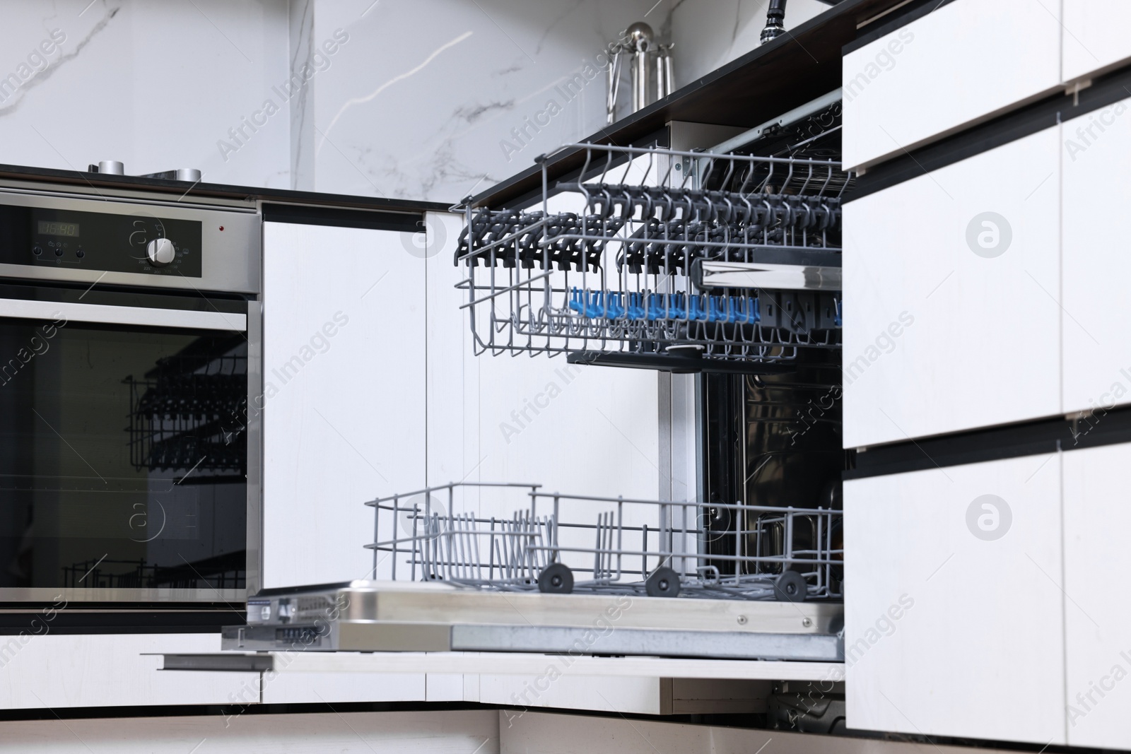 Photo of Open clean empty dishwasher in kitchen, low angle view