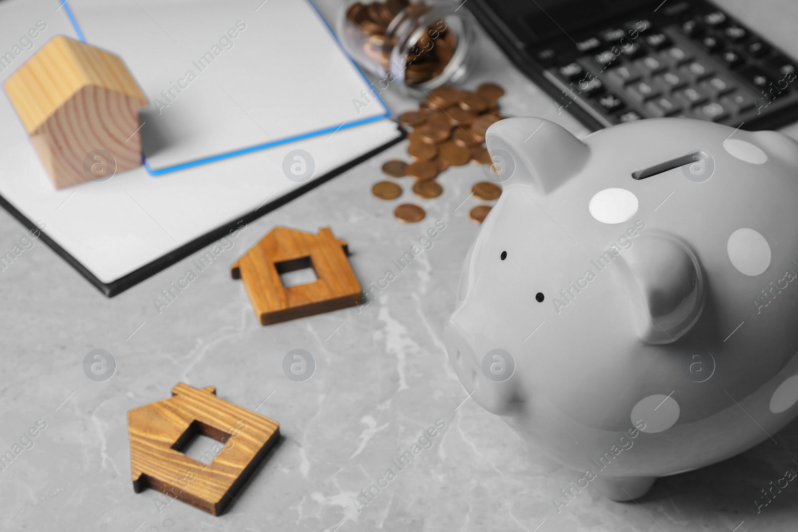 Photo of Piggy bank and wooden house models on grey marble table