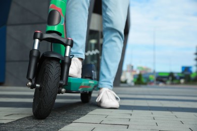 Photo of Man with modern electric kick scooter on city street, closeup. Space for text