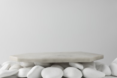 Photo of Presentation for product. Marble podium and white pebbles on light background. Space for text