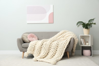 Photo of Knitted merino wool plaid on sofa in room