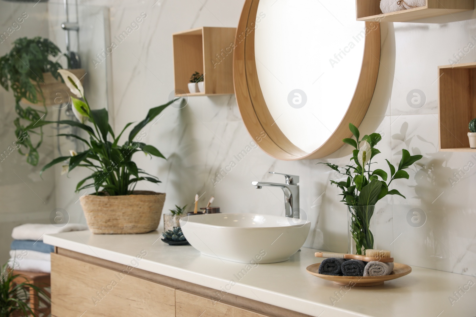 Photo of Beautiful green plants near vessel sink on countertop in bathroom. Interior design