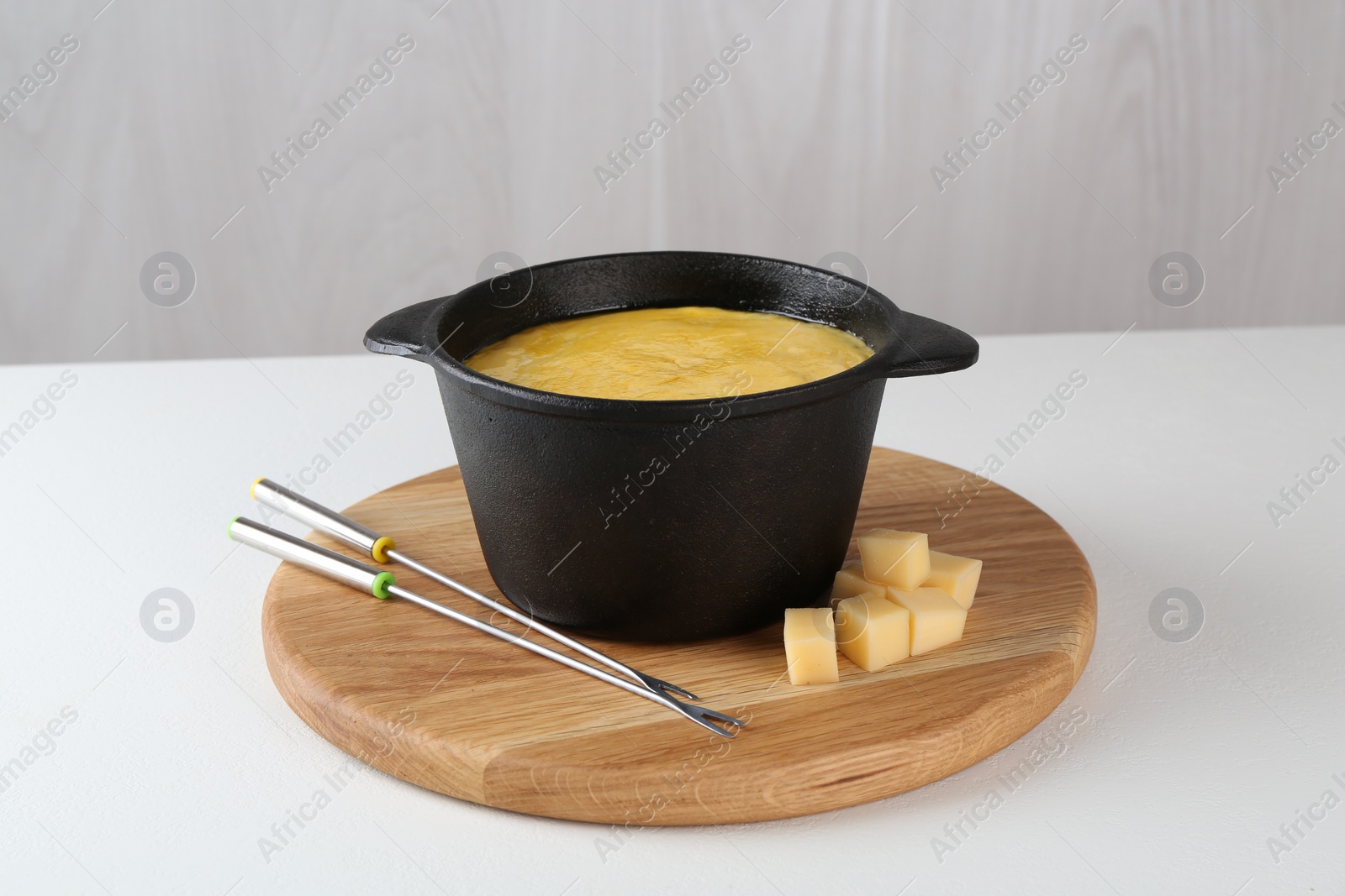 Photo of Fondue with tasty melted cheese and forks on white table