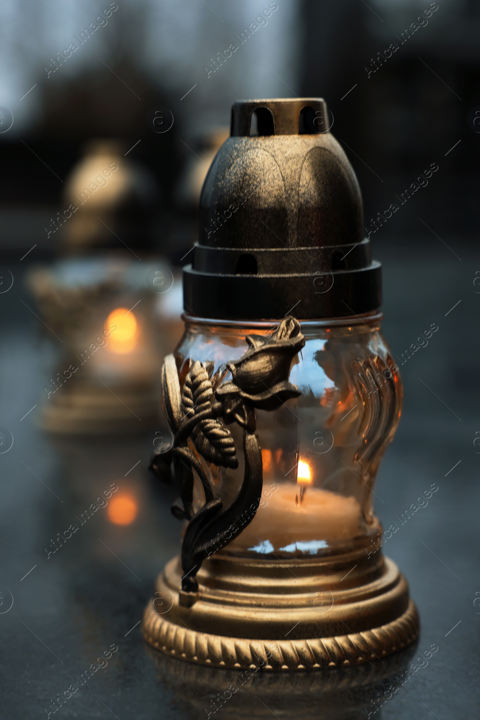 Photo of Grave light on granite surface at cemetery, closeup